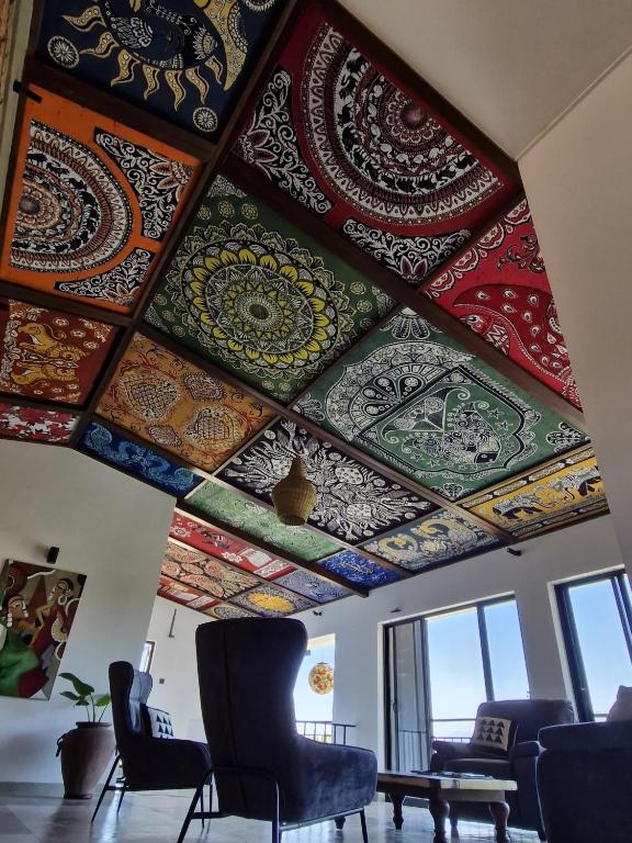 A living room with a striking ceiling of colorful patterned fabric panels and tall windows